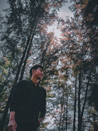 Portrait of young man standing against trees