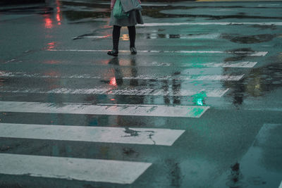 Low section of people walking on wet road