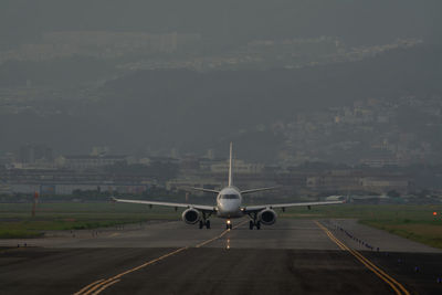 Airplane at airport runway against sky