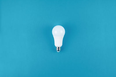 Low angle view of light bulb against blue background
