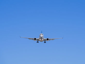 Low angle view of airplane flying against clear blue sky