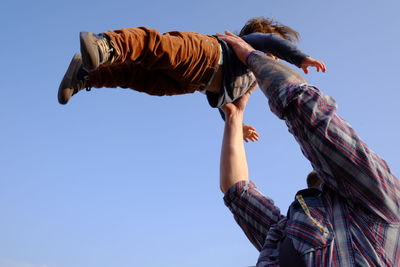 Father holding son against sky