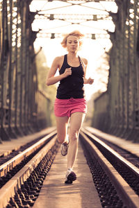 Full length portrait of woman standing on railroad track