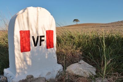 Information sign on field against sky