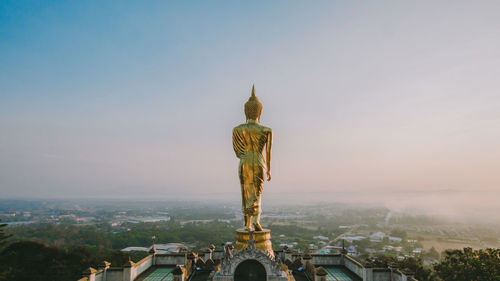 The buddha statue is on the top of a high hill.