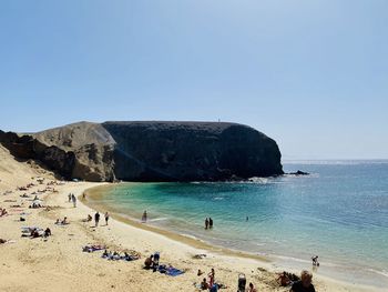 People on beach against clear sky - lanzarote and papagayo beach