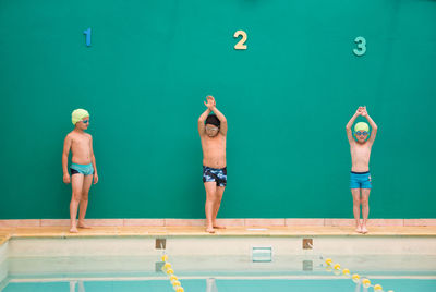 Full length of boys standing by swimming pool