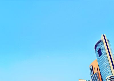 Low angle view of buildings against clear blue sky