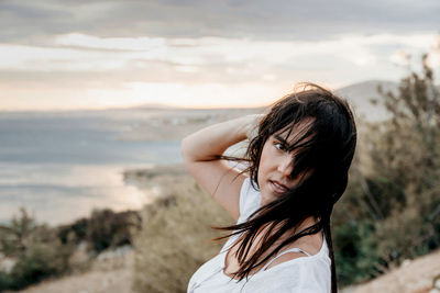 Portrait of woman standing on beach against sky