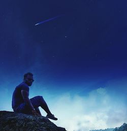 Low angle view of man sitting against sky at night