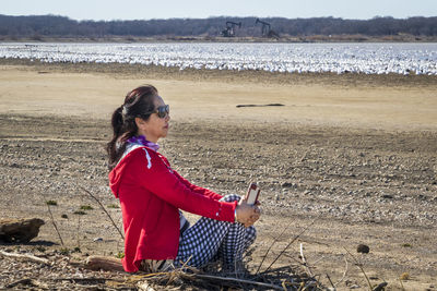 Side view of woman sitting on beach