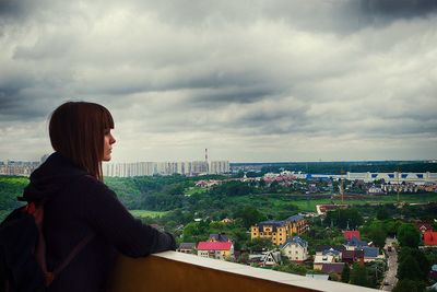 Woman looking at city buildings against sky