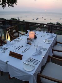 Chairs and tables at restaurant against sea during sunset