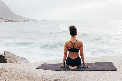 Young woman sitting on rock at beach