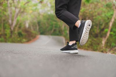 Low section of man skateboarding on road