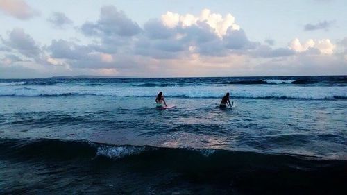 People on beach against sky during sunset