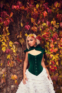 Portrait of young woman standing with autumn leaves