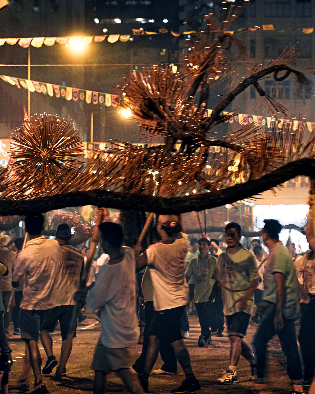 REAR VIEW OF PEOPLE WALKING AT ILLUMINATED STREET