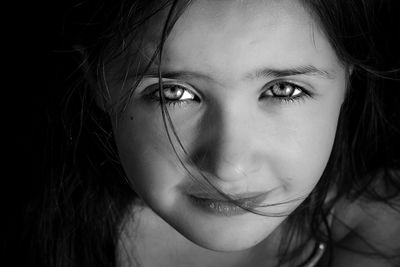 Close-up portrait of girl smiling against black background