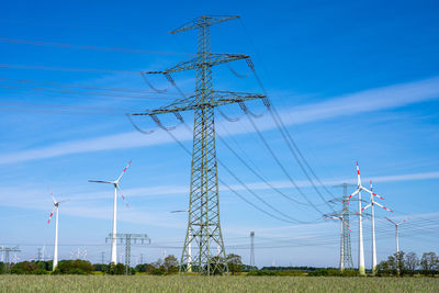 Electricity pylon on field against blue sky