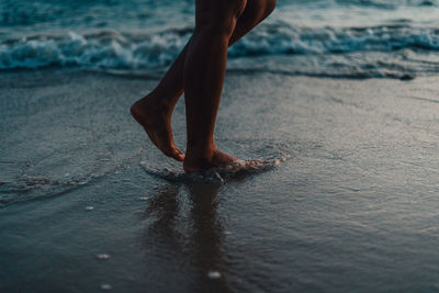 Low section of man walking on sand