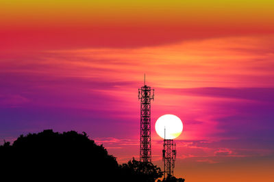 Low angle view of communications tower against orange sky