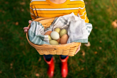 A boy holding a basket full of fresh chicken eggs
