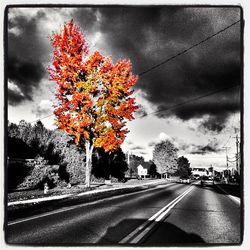 Cars on road against cloudy sky