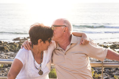 Close-up of man kissing on woman forehead at beach