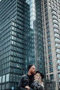 Low angle view of woman standing against modern building in city