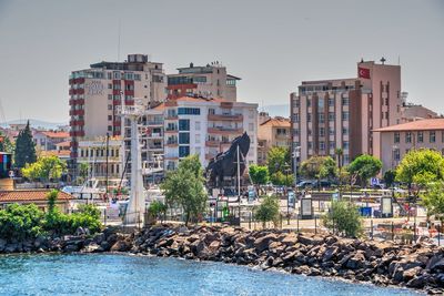 Buildings by sea against clear sky