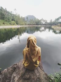 Rear view of man looking at lake against sky