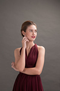 Portrait of young woman against gray background