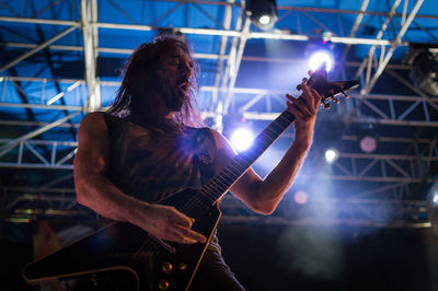 Man playing guitar at illuminated music concert