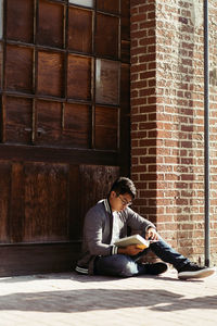 Young man sitting on brick wall