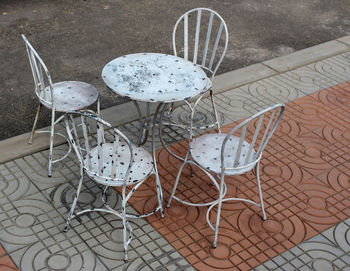 High angle view of empty chairs and table at sidewalk cafe against building