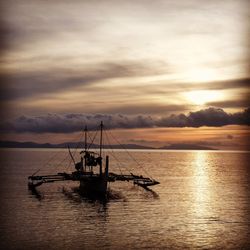 Silhouette sailboat in sea against sky during sunset