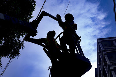 Low angle view of men working against sky