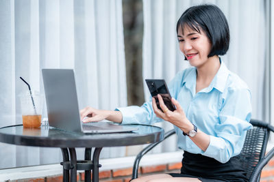 Young businesswoman using mobile phone at table