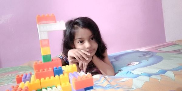 Portrait of girl with toy on table at home