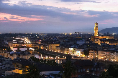 Illuminated city against sky during sunset