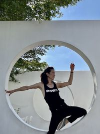 Portrait of young woman standing against sky