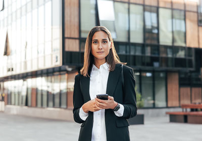 Portrait of young businesswoman standing in city