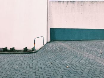 Empty footpath by wall in city