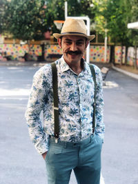 Portrait of man wearing hat standing on road