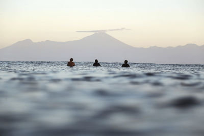 Surfers on surfboard on the sea waiting for a wave, volcano rinjani