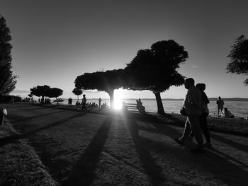 Silhouette people on field against clear sky