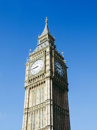 Low angle view of clock tower against blue sky