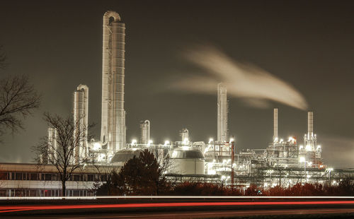 Illuminated factory against sky at night