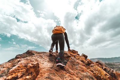 Rear view of person on rock against sky